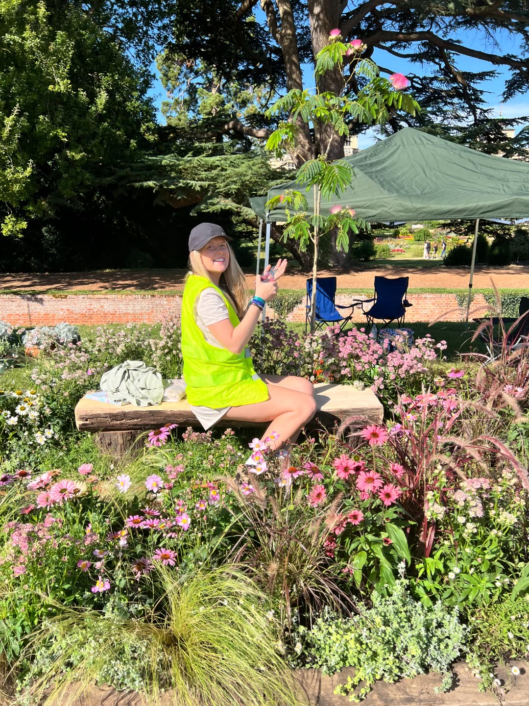 Emma Atkinson, landscape architect and garden designer, sitting in one of her show gardens during build, surrounded by pink echinacea and ornamental grasses.